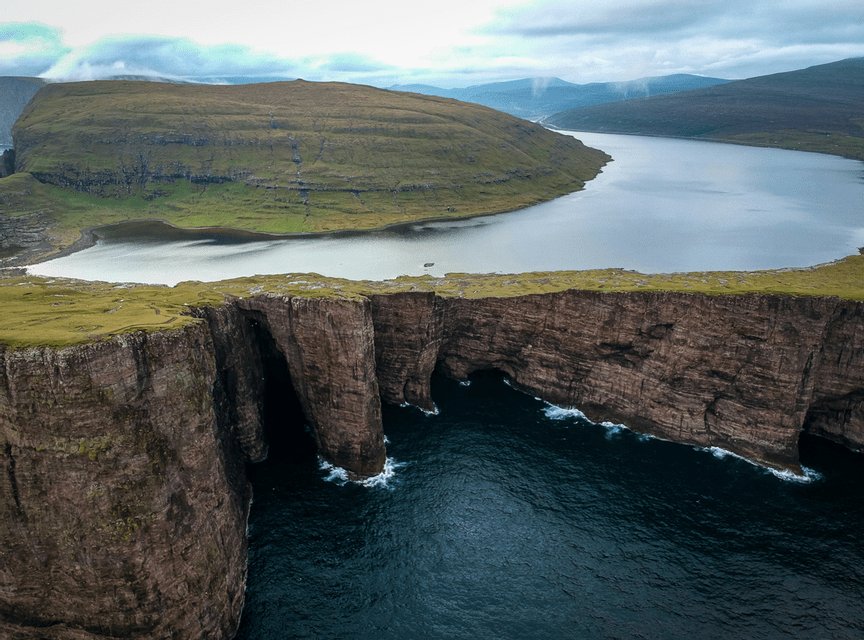 Vue aérienne d'un grand lac situé sur un plateau verdoyant haut au-dessus de l'océan, séparé par des falaises rocheuses abruptes.
