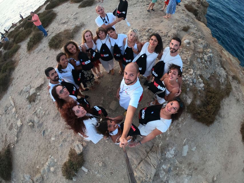 Selfie de un grupo de WeRoad posando en círculo en un acantilado junto al mar.