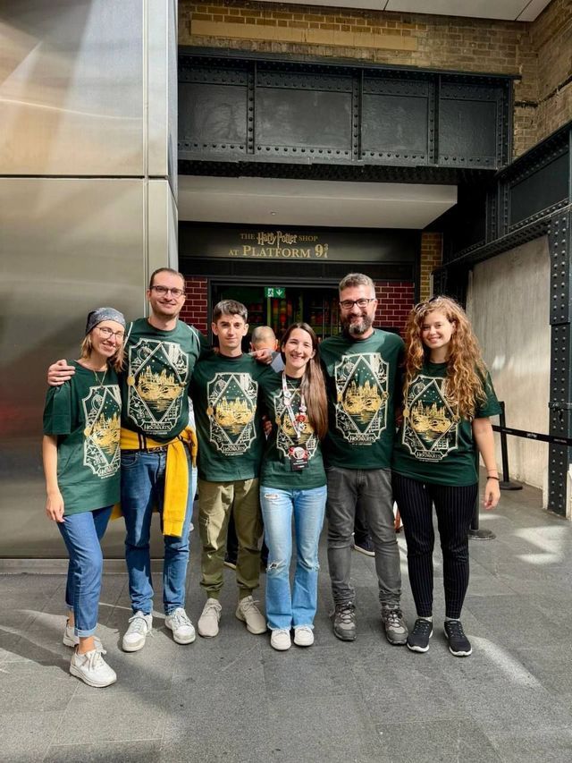 Un gruppo WeRoad in viaggio con magliette verdi abbinate, in posa davanti all'ingresso del negozio di Harry Potter.