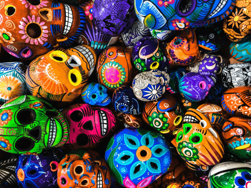 Vue plongeante rapprochée de nombreux crânes Calavera colorés, peints à la main, avec des motifs floraux et géométriques complexes.