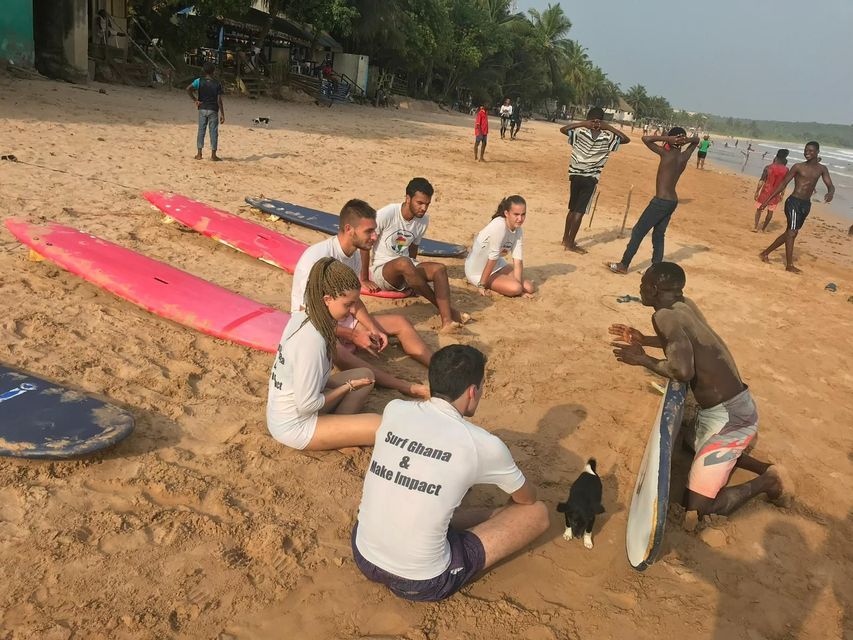 Un gruppo WeRoad in spiaggia sabbiosa con tavole da surf, riunito per una lezione con un istruttore locale.