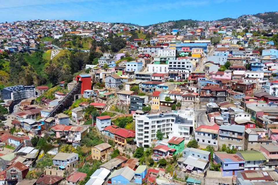 Una vista aerea di una città colorata costruita su una ripida collina, con una funicolare che sale il pendio.