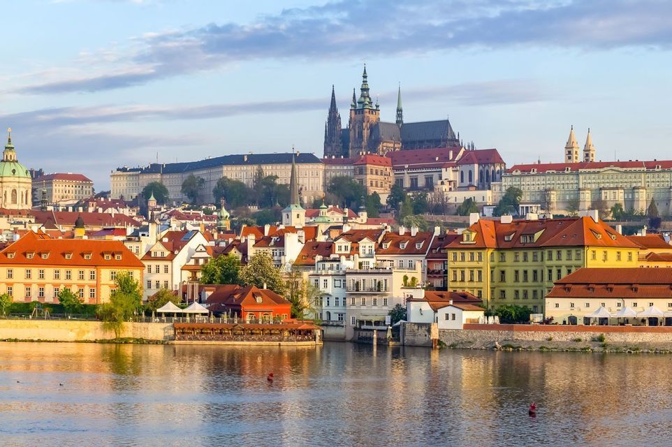 Colourful houses along the Vltava river with Prague Castle rising behind them.