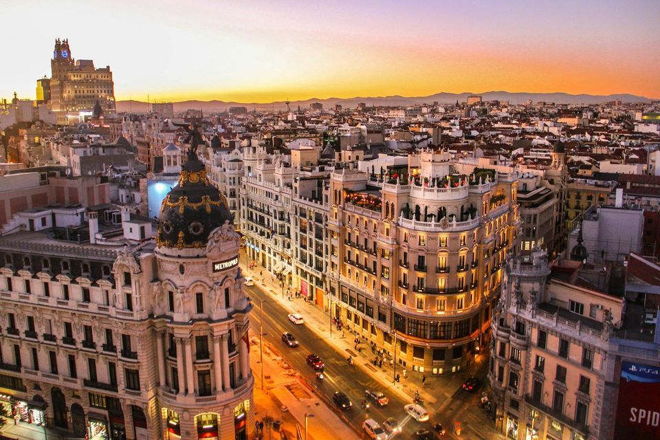 An aerial view of a cityscape at sunset, featuring the ornate Metropolis building and traffic on the street below.