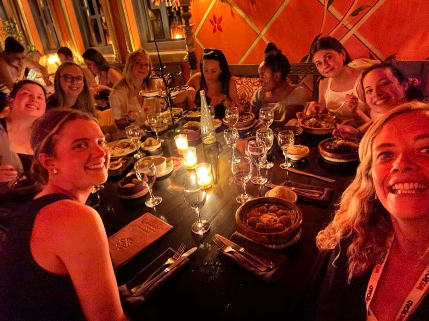 Un groupe de voyage WeRoad sourit pour un selfie tout en dînant ensemble à une longue table aux chandelles dans un restaurant.