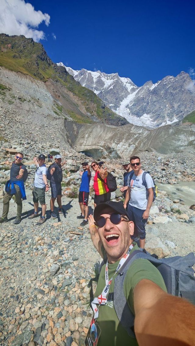 Un uomo si scatta un selfie durante il suo viaggio di gruppo WeRoad su un sentiero roccioso, con le montagne innevate sullo sfondo.