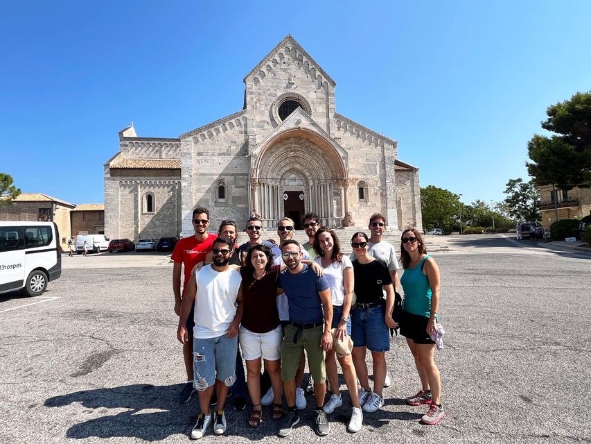 Un gruppo WeRoad posa per una foto in una piazza assolata davanti a una grande cattedrale in pietra.