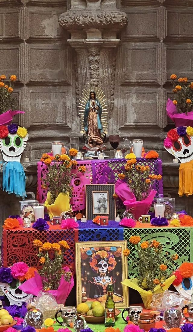 Un altare colorato del Giorno dei Morti decorato con calendule, papel picado, teschi, ritratti e una statua della Vergine Maria.
