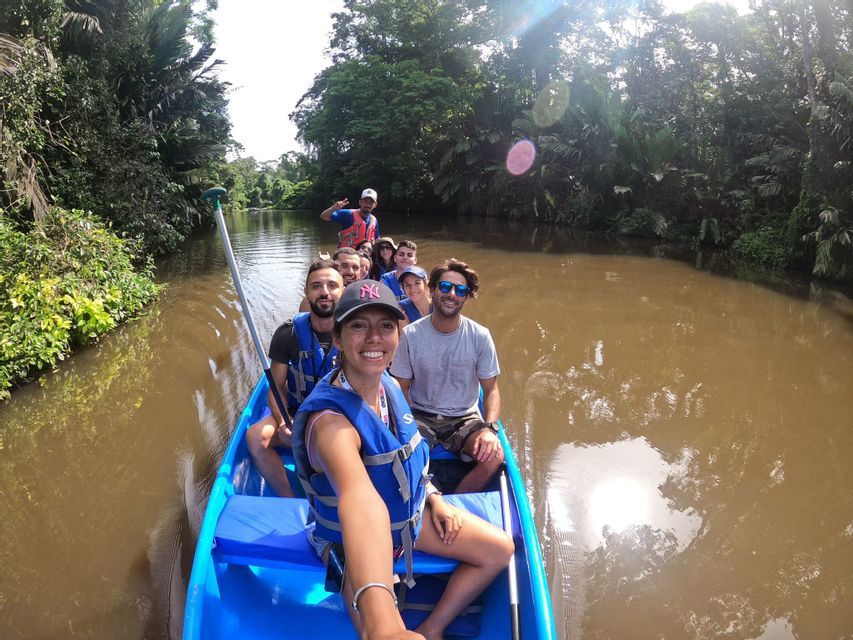 Una donna si scatta un selfie con il suo gruppo WeRoad in una canoa blu su un fiume in una giungla lussureggiante.