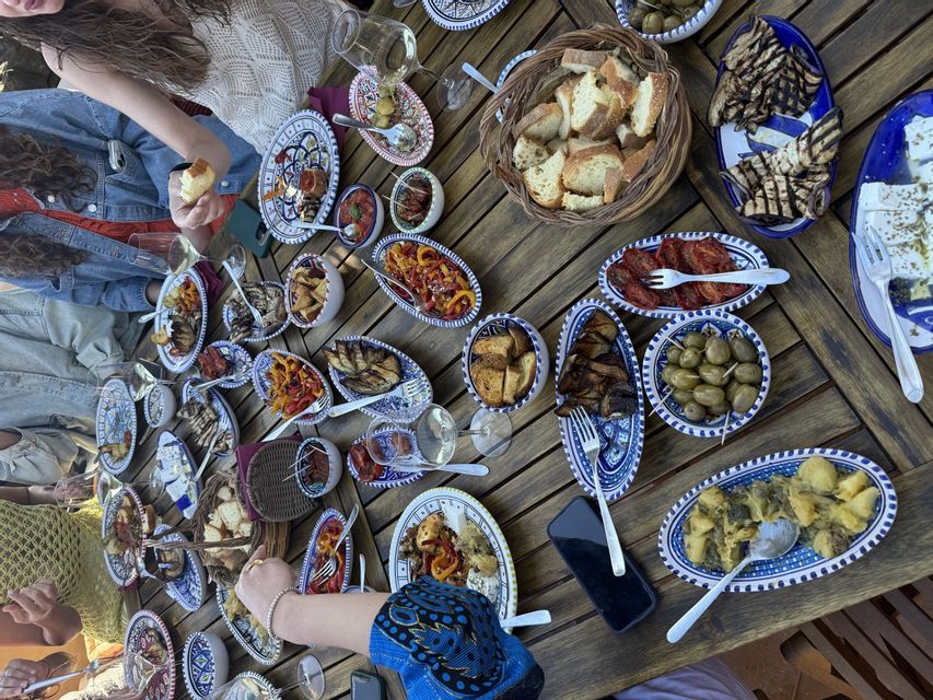 Vista dall'alto di un gruppo WeRoad in viaggio che condivide antipasti serviti in tanti piccoli piatti su un tavolo di legno.