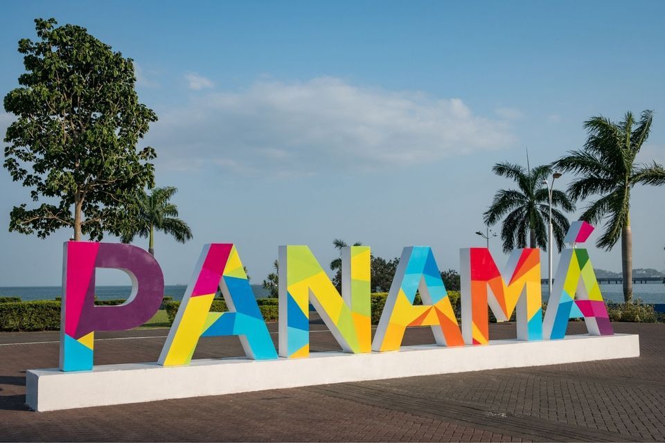Das Wort 'PANAMA' in großen, bunten, dreidimensionalen Buchstaben auf einer Promenade am Meer mit Palmen.