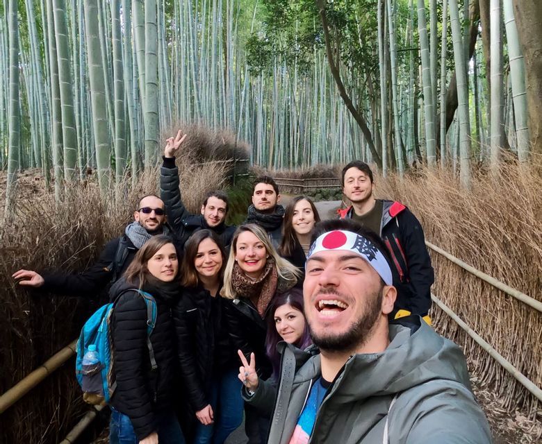 Un gruppo WeRoad scatta un selfie sorridente su un sentiero all'interno di una fitta foresta di bambù.