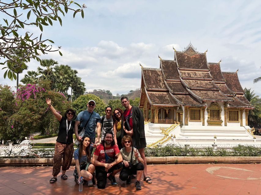 Un gruppo WeRoad posa per una foto in un cortile di fronte a un tradizionale tempio dai tetti multipli.