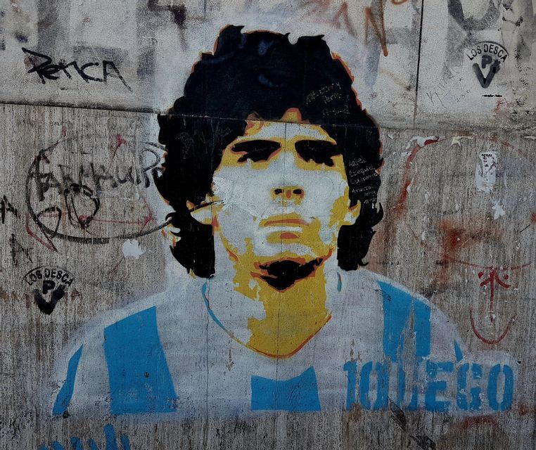 Un graffito a stencil di Diego Maradona su un muro imbrattato, che lo raffigura con la maglia della nazionale argentina.