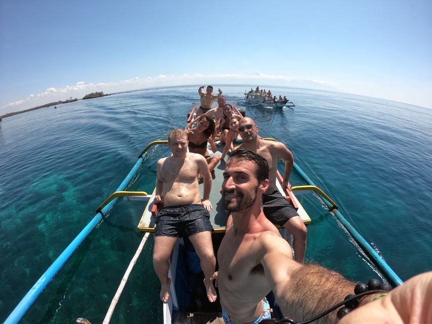 Un groupe WeRoad prend un selfie sur un bateau étroit naviguant sur une eau turquoise claire par une journée ensoleillée.