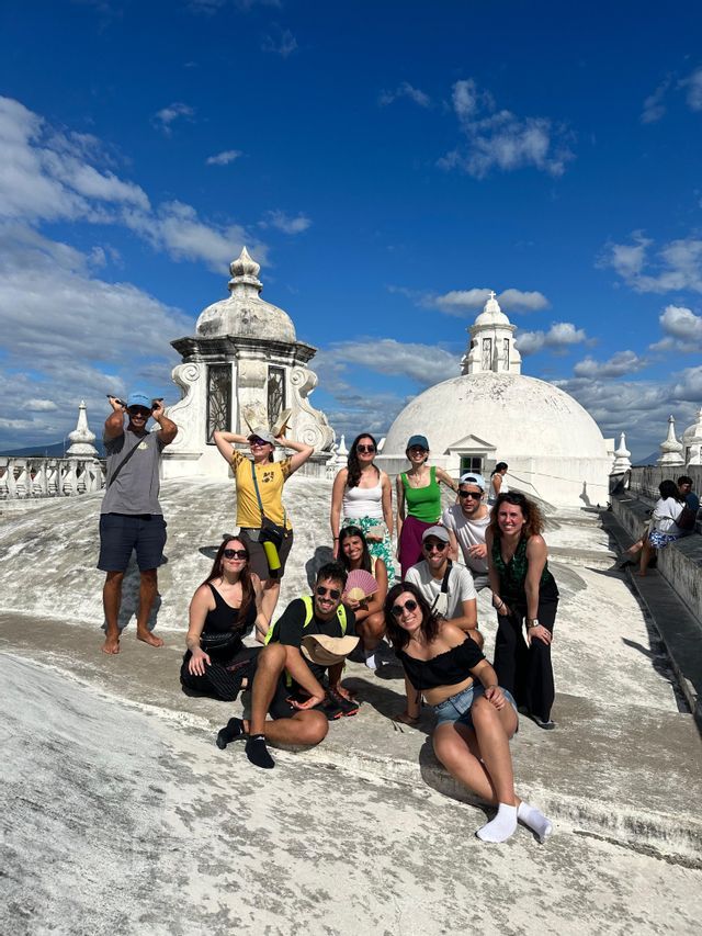 Un voyage de groupe WeRoad pose pour une photo sur un toit blanc avec des dômes sous un ciel bleu.