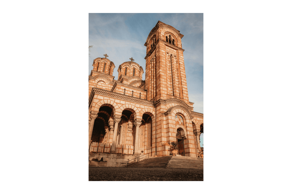 Inquadratura dal basso di un'ornata chiesa in pietra con un alto campanile e cupole contro un cielo blu.