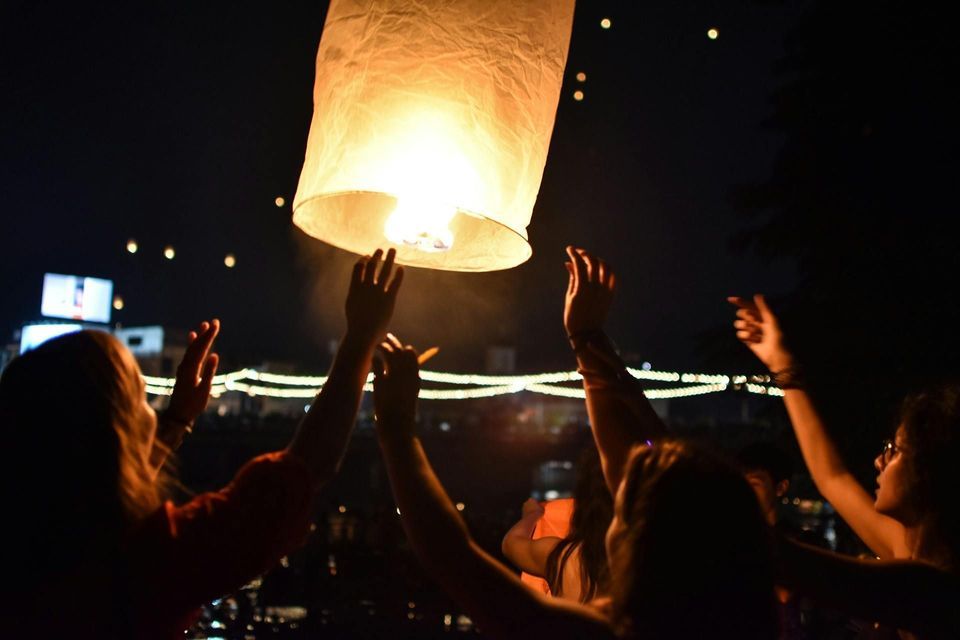 Un viaggio di gruppo WeRoad rilascia una grande lanterna di carta luminosa nel cielo notturno tra altre lanterne fluttuanti.