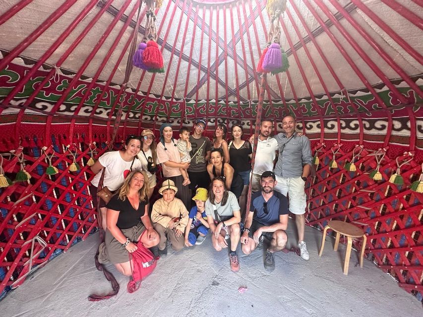 Un voyage de groupe WeRoad prend la pose pour une photo à l'intérieur d'une yourte rouge, traditionnelle et richement décorée.