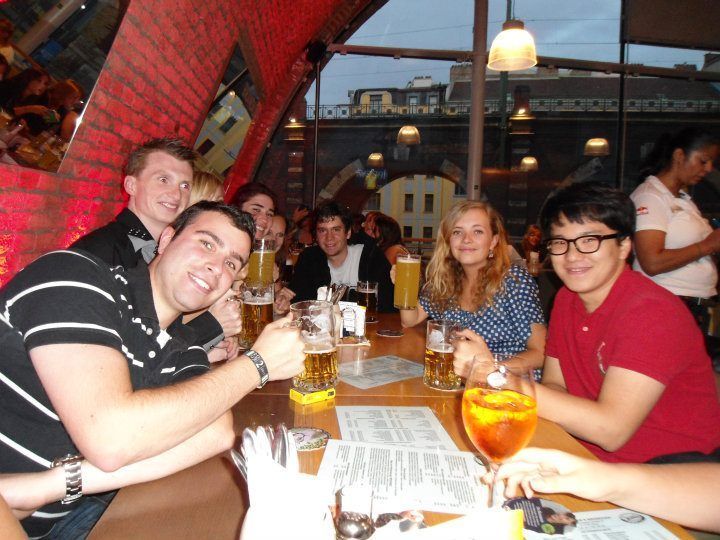 Un voyage de groupe WeRoad avec des gens souriants devant l'appareil photo, attablés dans un pub avec des verres de bière.
