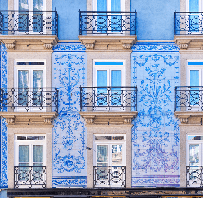 La facciata di un edificio decorato con piastrelle azulejo a motivi blu e bianchi e piccoli balconi con ringhiere in ferro battuto.