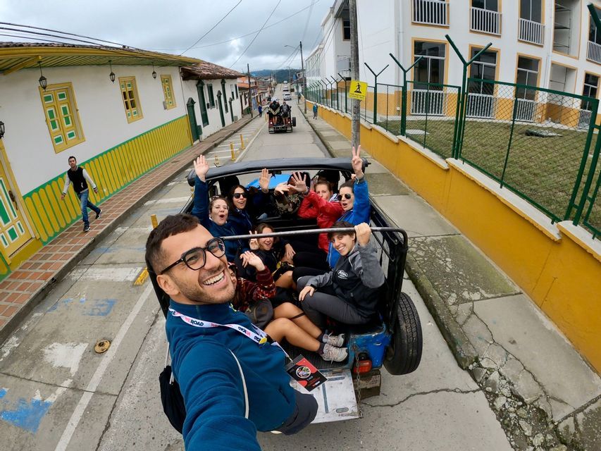 Un uomo si scatta un selfie sorridente con il gruppo WeRoad in viaggio, a bordo di un veicolo scoperto, in una strada cittadina.