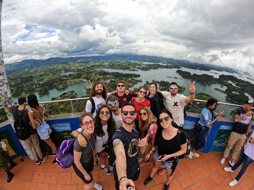 Un viaggio di gruppo WeRoad scatta un selfie da un punto panoramico che si affaccia su un vasto paesaggio di laghi e colline verdi.