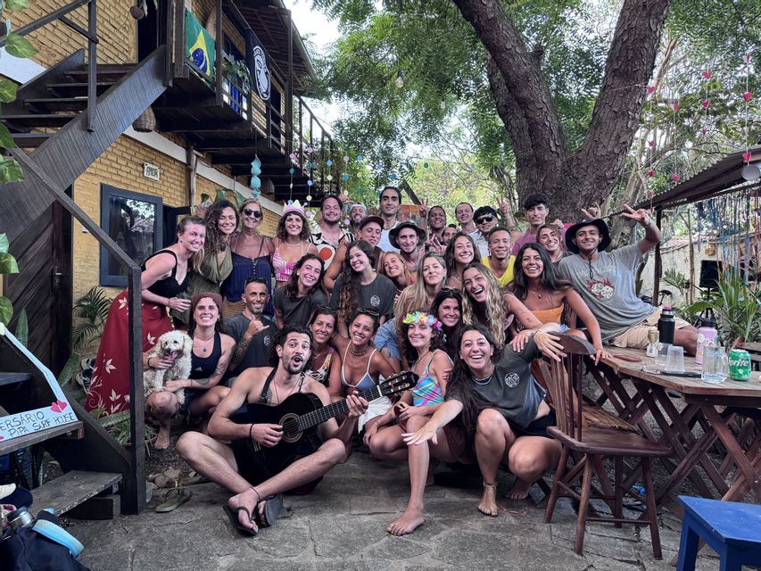 Un folto gruppo WeRoad in viaggio posa insieme per una foto in un cortile, con un uomo che suona la chitarra in primo piano.