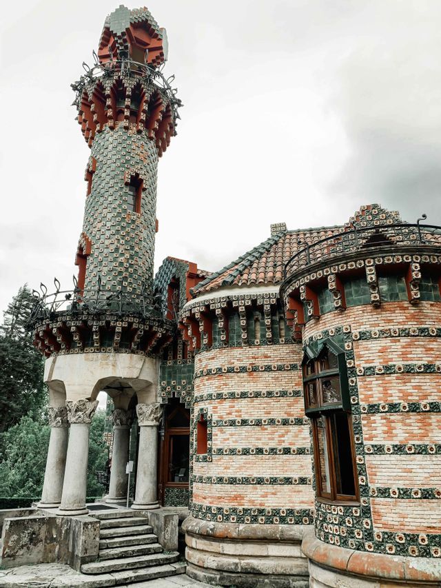 Un edificio decorato con un'alta torre rivestita di tegole verdi e rosse e muri in mattoni con motivi decorativi.