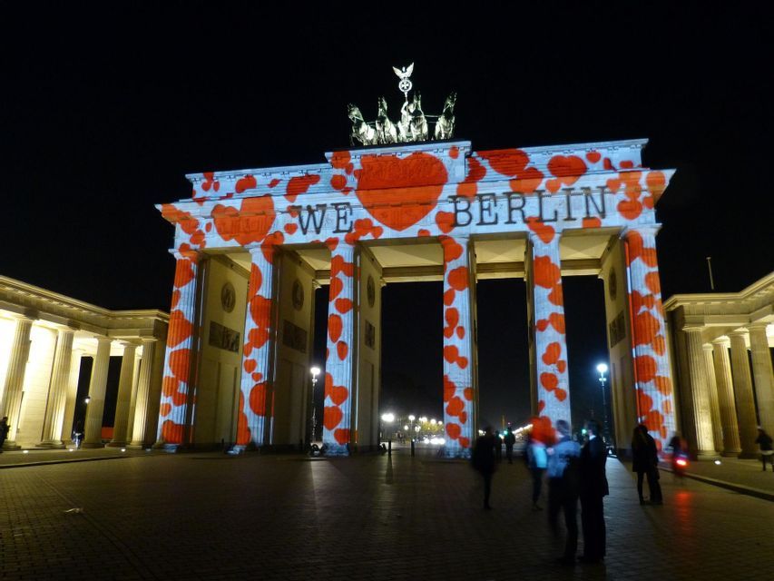 La Porta di Brandeburgo è illuminata di notte con una proiezione di cuori rossi e il testo "WE ❤️ BERLIN" sulla sua facciata.