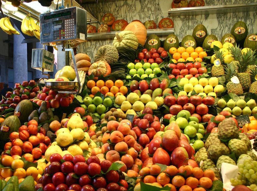 A colorful abundance of fresh fruits, including apples, oranges, and pineapples, displayed on a market stall with a weighing scale.