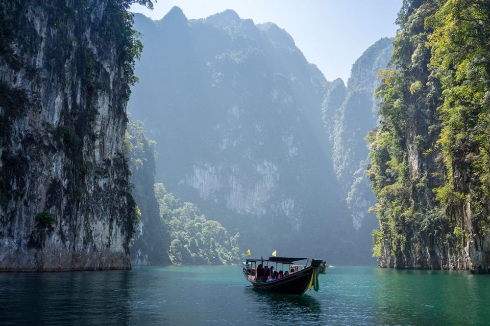 Un voyage de groupe WeRoad en pirogue à longue queue sur des eaux turquoises, entre d'imposantes falaises calcaires verdoyantes.