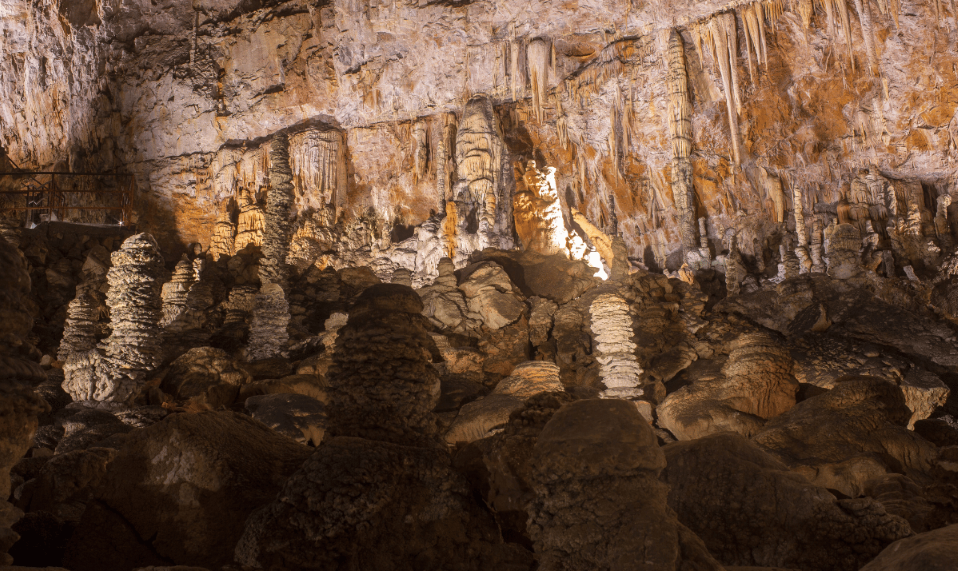 Una vasta grotta sotterranea piena di stalattiti e stalagmiti illuminate.