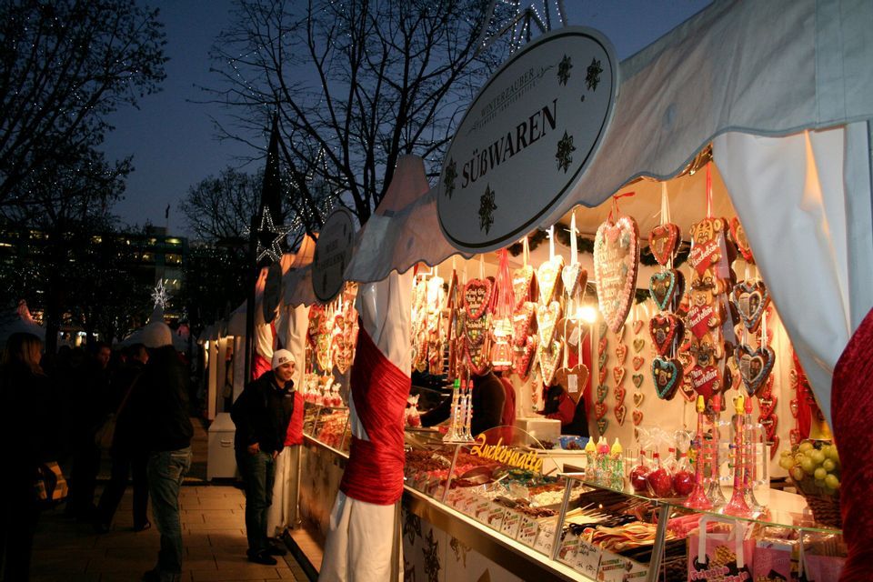 Una luminosa bancarella di dolci in un mercato notturno, con cuori di pan di zenzero e caramelle esposte.