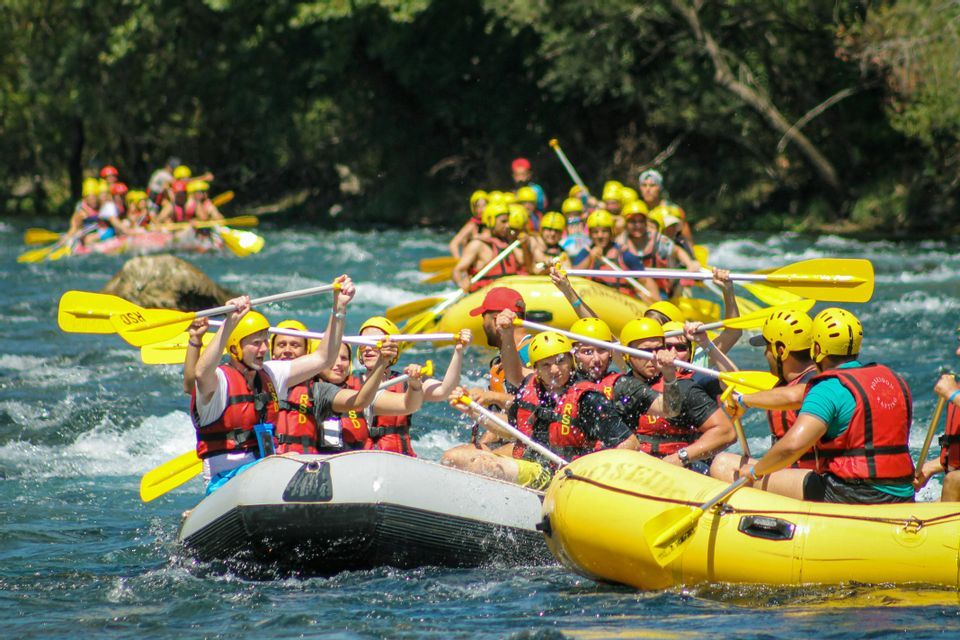 Un viaggio di gruppo WeRoad su gommoni gialli lungo un fiume, esultando con le pagaie alzate in aria.