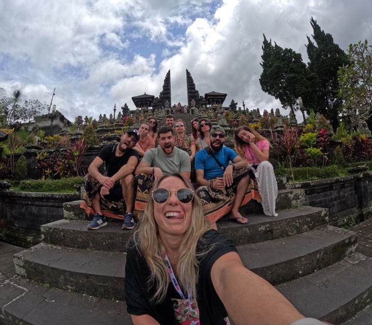 Un gruppo WeRoad si scatta un selfie giocoso sui gradini di un complesso di templi ornato sotto un cielo nuvoloso.