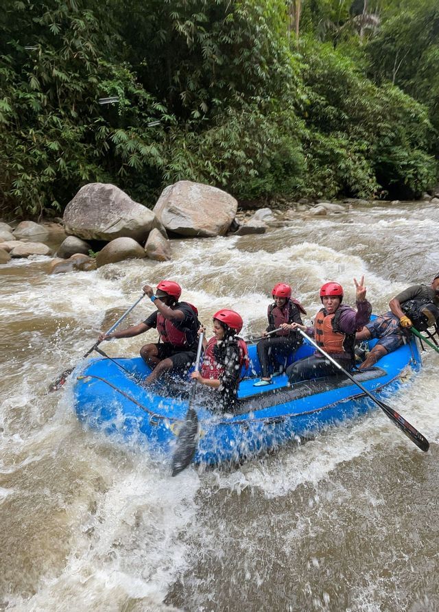 Un voyage en groupe WeRoad: rafting en eaux vives sur une rivière agitée, à bord d'un radeau gonflable bleu au milieu d'une jungle luxuriante.