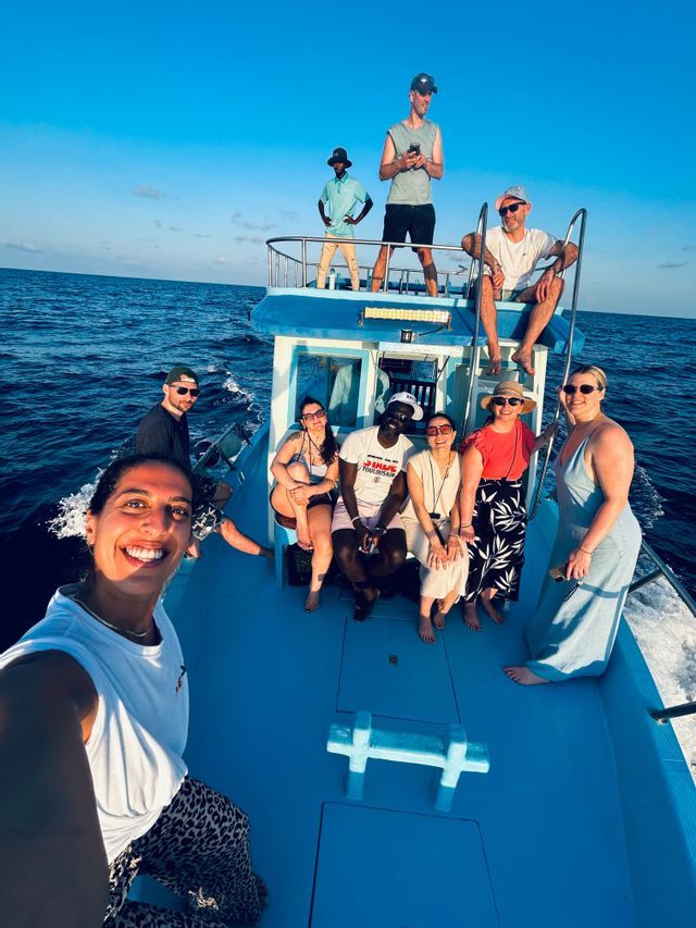 Eine WeRoad-Gruppe macht ein Selfie auf einem blauen Boot, das unter klarem Himmel auf dem offenen Meer segelt.