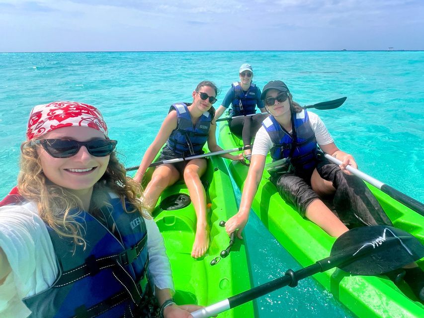Vier Frauen einer WeRoad Gruppe machen ein Selfie beim Kajakfahren in klarem, türkisfarbenem Wasser.