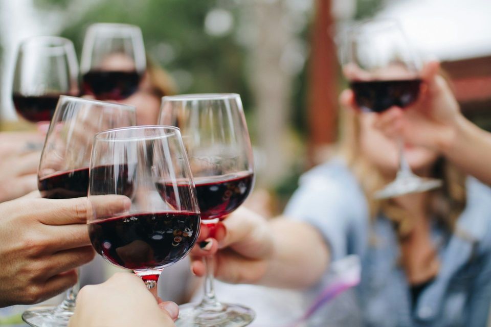 Brindisi di gruppo WeRoad con calici di vino rosso in primo piano.