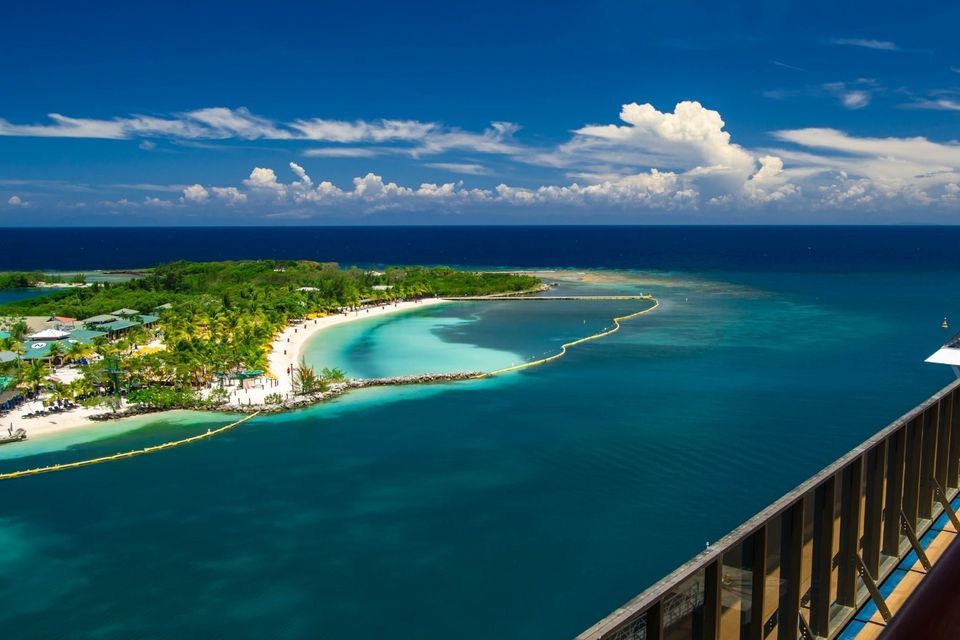 Eine Luftaufnahme einer tropischen Insel mit einem weißen Sandstrand und einer türkisfarbenen Bucht, umgeben vom tiefblauen Ozean.