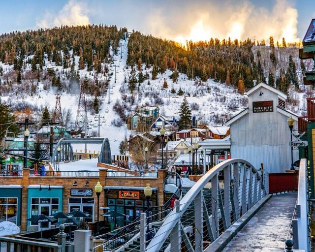 Un puente domina el pueblo en la estación de esquí de Park City Mountain, con pistas cubiertas de nieve y telesillas visibles al amanecer.