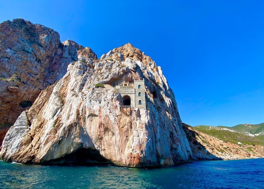 The Porto Flavia mining port, a stone structure carved into a sheer sea cliff above the blue water.