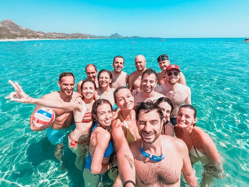 A WeRoad group trip smiling and taking a selfie while standing together in clear turquoise water.