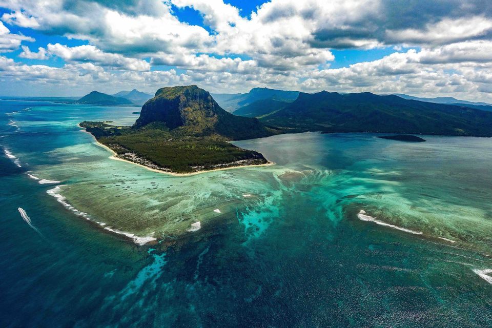 Una vista aerea di una penisola montuosa e l'illusione ottica di una cascata sottomarina nell'oceano turchese.