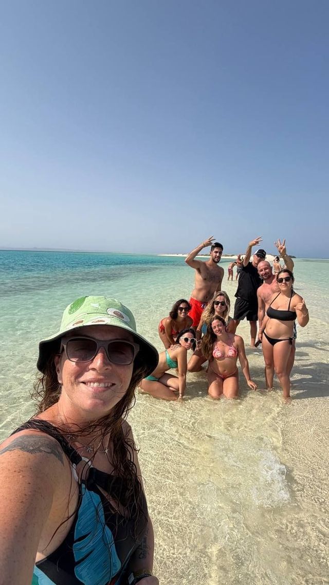 Un gruppo WeRoad scatta un selfie mentre posa nell'acqua bassa e turchese di un banco di sabbia.