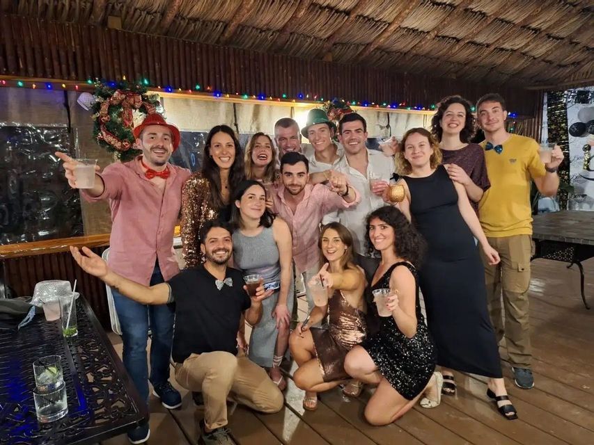 A WeRoad group trip smiling and posing together for a photo at a festive party with Christmas decorations.