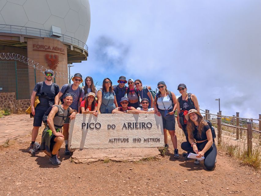 Un gruppo WeRoad in viaggio si scatta una foto nei pressi del segnale di vetta del Pico do Arieiro, su una montagna.