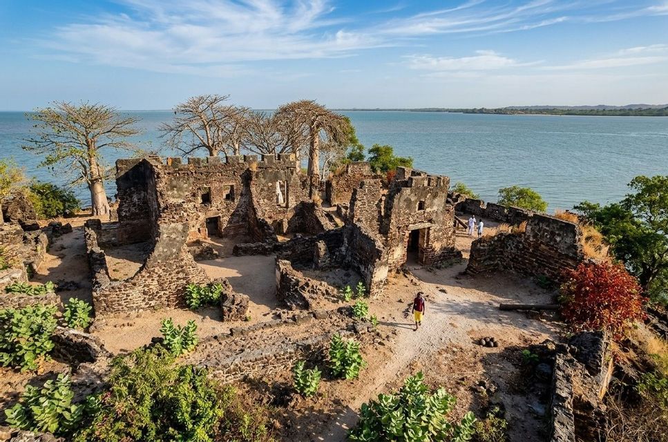 Vista aerea delle rovine in pietra di un'antica fortezza su una collina affacciata sull'acqua, con una persona che cammina su un sentiero.