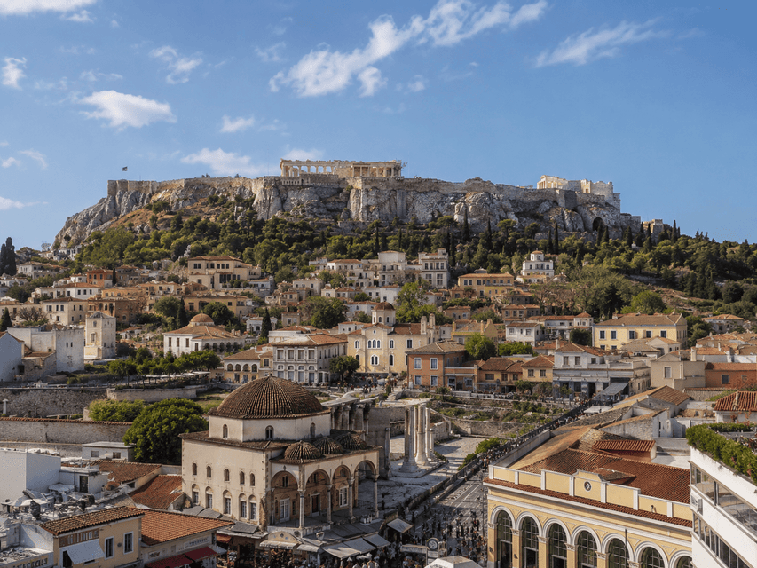 L'Acropoli si trova su una collina rocciosa che domina gli edifici storici e i tetti di Atene in una giornata di sole.